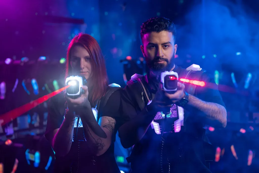Frau und mann zielen mit ihren waffen beim Lasertag in der laserzone