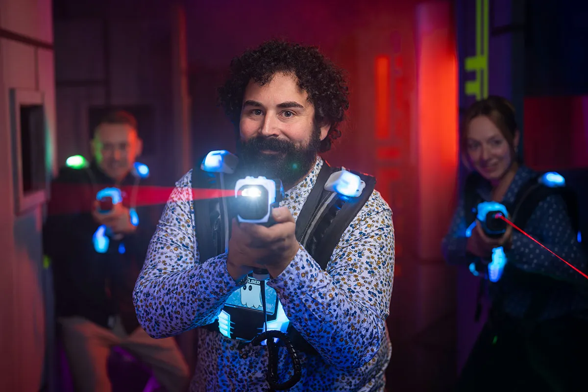 teamevent lasertag mann zielt mit dem laser kollegen im hintergrund