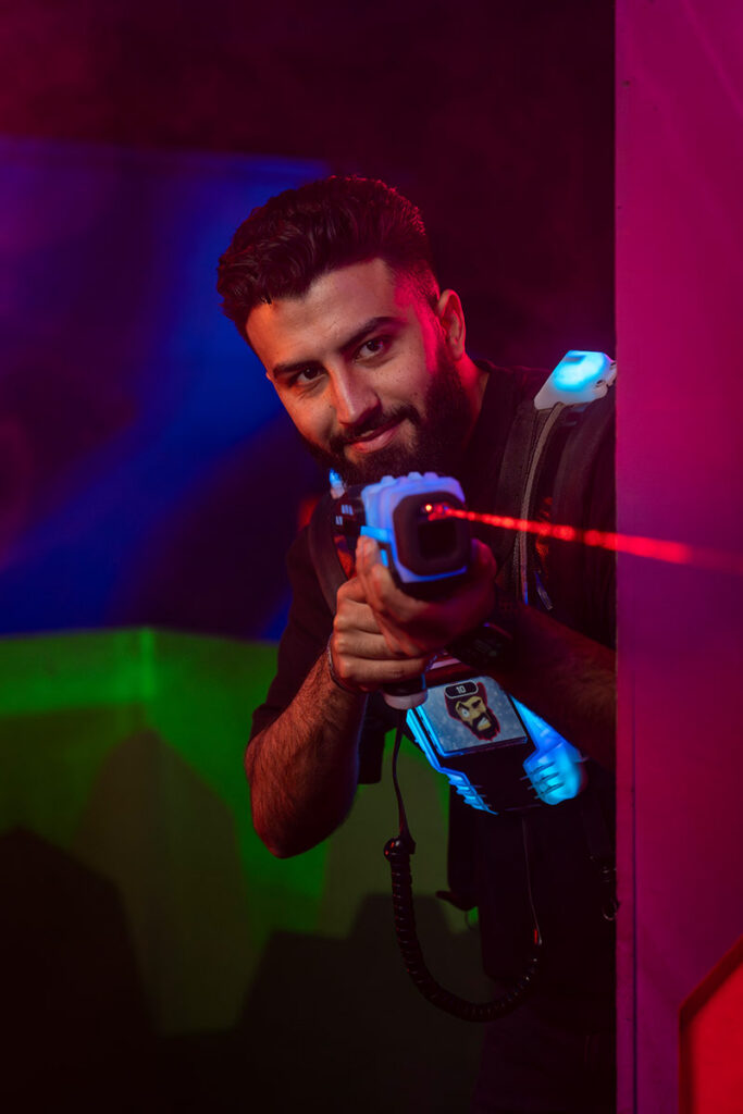 Mann zielt mit dem Laser und schaut um die Ecke beim Lasertag