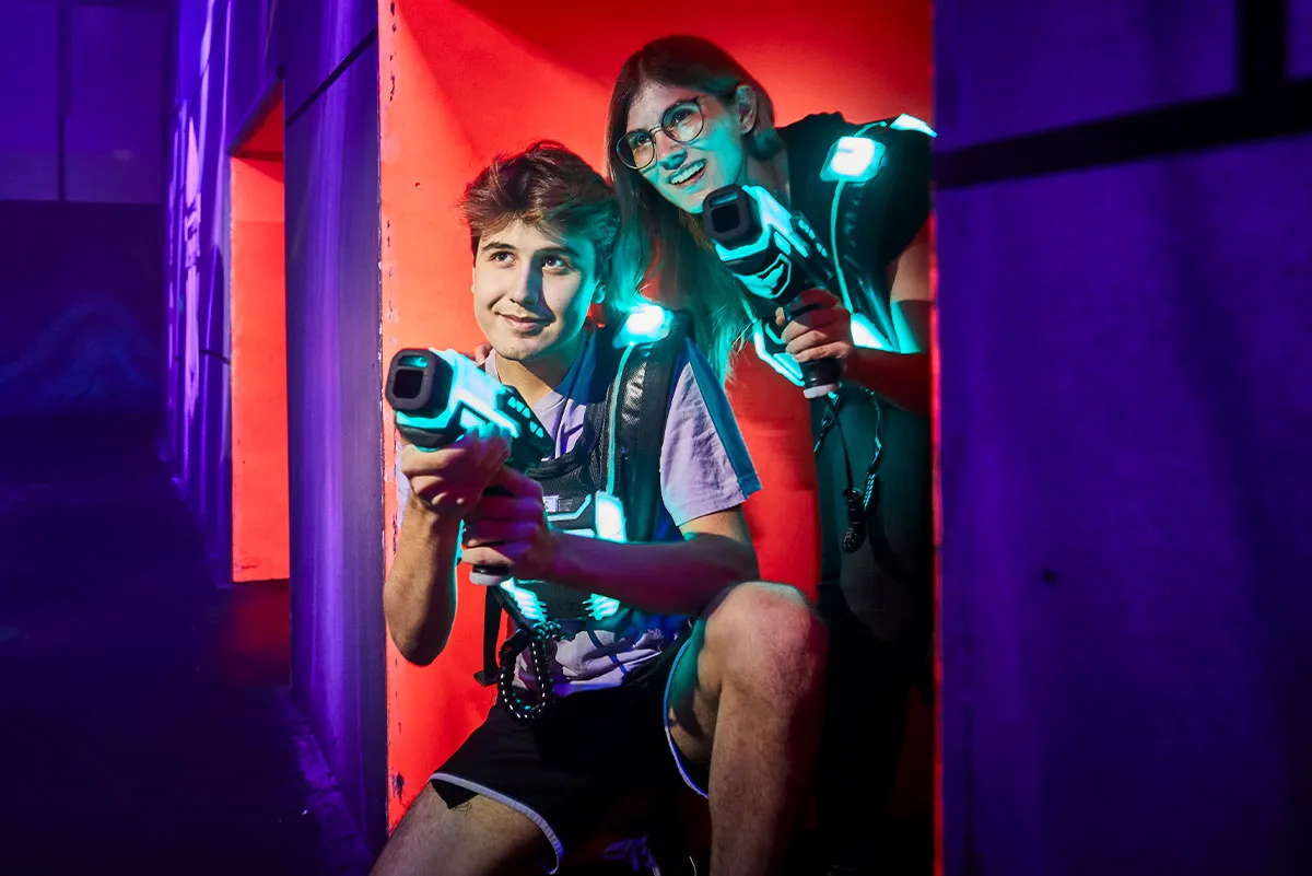 zwei jugendliche spielen lasertag und verstecken sich